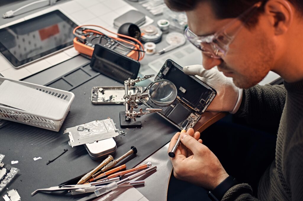 serviceman uses magnifier screwdriver repair damaged smartphone electronic workshop